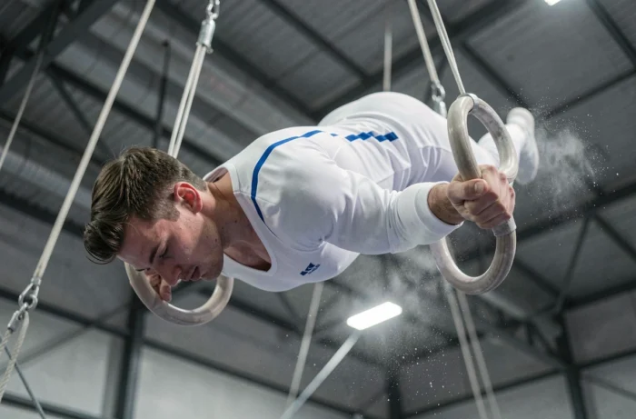 Gymnaste masculin réalisant une croix de fer aux anneaux lors d'une compétition de gymnastique artistique